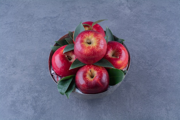 Un bol de pommes avec des feuilles sur la surface sombre