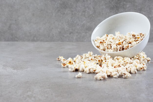 Bol de pop-corn dispersé sur fond de marbre. Photo de haute qualité