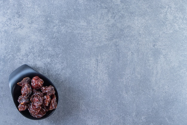 Un bol de prune séchée, sur le fond de marbre.