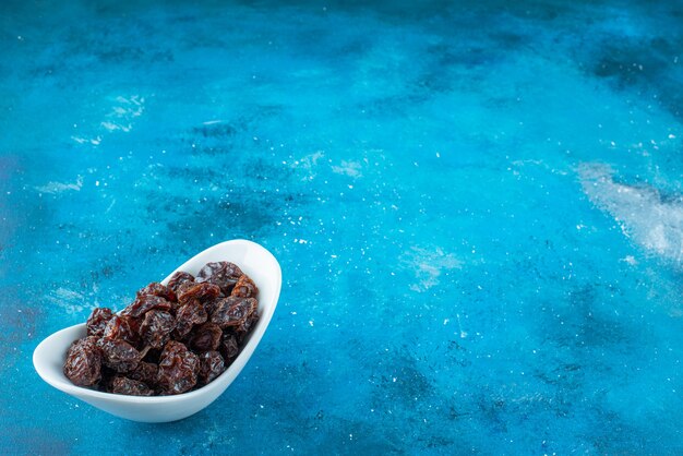 Un bol de prunes séchées sur la surface bleue