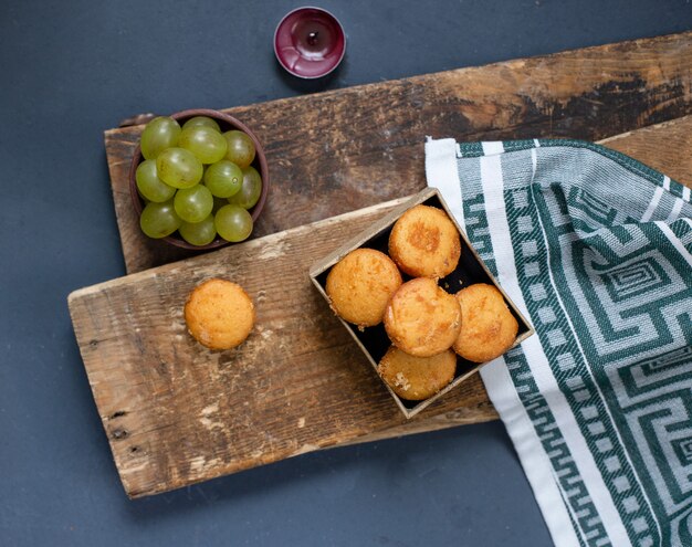 bol de raisins verts et muffins sur le morceau de bois