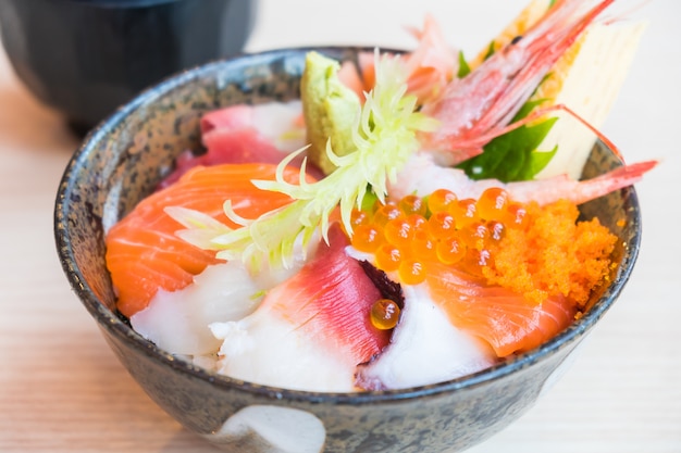 Bol de riz japonais avec des fruits de mer sashimi sur le dessus