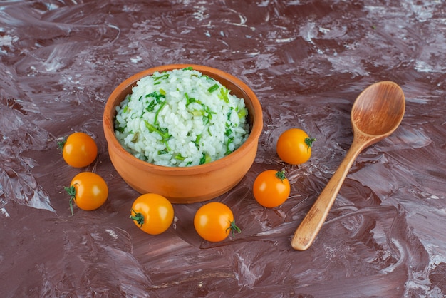 Bol de riz, tomates et cuillère, sur le fond de marbre.