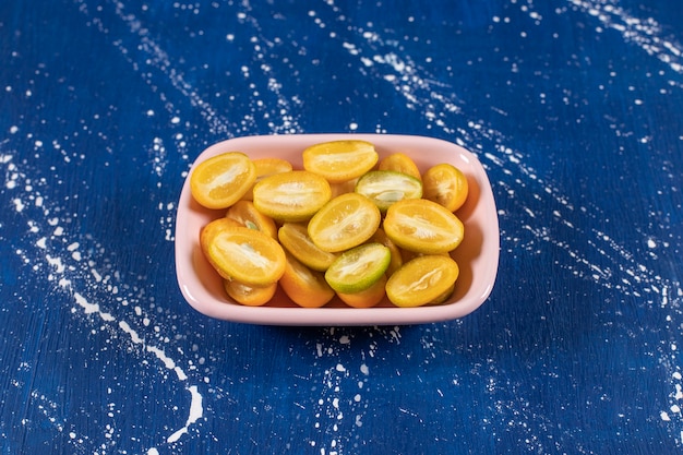 Photo gratuite bol rose de fruits frais tranchés de kumquat sur une surface en marbre