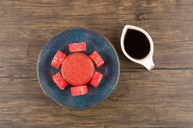 Bol de rouleaux de sushi et de caviar rouge sur table en bois avec du soja