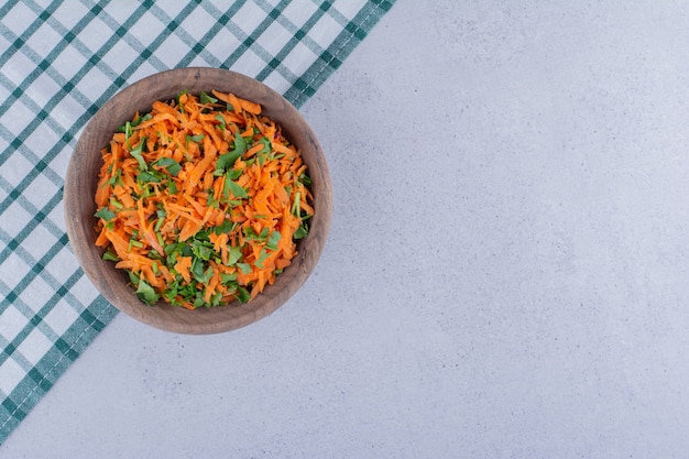 Bol de salade de carottes sur une nappe sur fond de marbre.