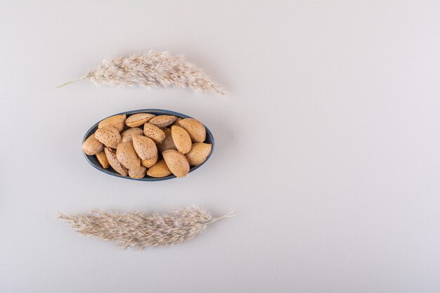 Bol sombre d'amandes biologiques décortiquées sur fond blanc. photo de haute qualité