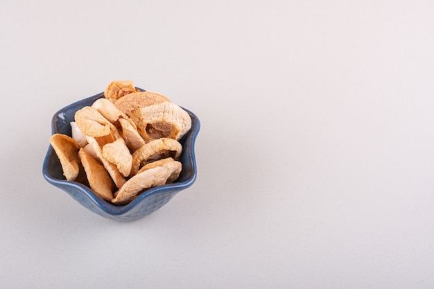 Bol sombre d'anneaux de pomme secs placés sur une table blanche. photo de haute qualité