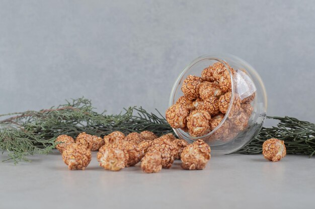 Bol en verre tombé sur une branche, renversant du pop-corn enrobé de bonbons sur une table en marbre.