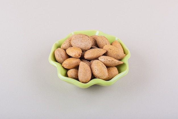 Photo gratuite bol vert d'amandes biologiques décortiquées sur fond blanc. photo de haute qualité