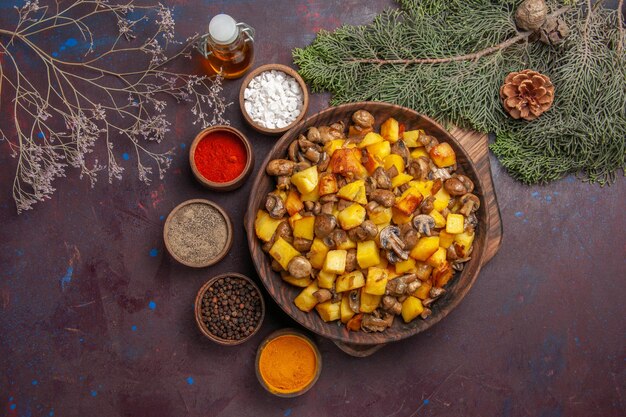 Bol avec vue de dessus avec bol de nourriture avec pommes de terre frites et champignons différentes épices et huile entre les branches d'arbres et les cônes