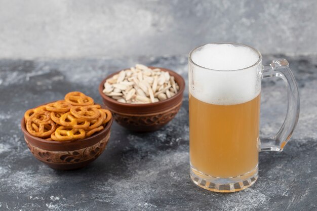 Bols de bretzels salés et graines de tournesol avec chope de bière sur la surface en marbre