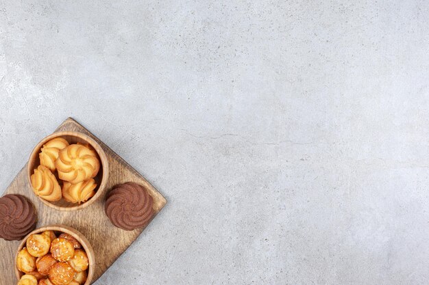 Bols de cookies à côté de cookies bruns sur planche de bois sur fond de marbre. Photo de haute qualité
