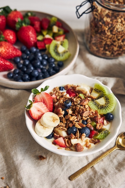 Photo gratuite bols de granola avec du yogourt, des fruits et des baies sur une surface blanche