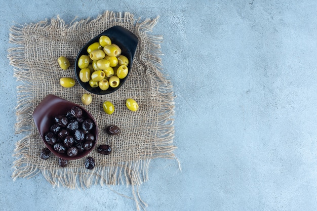 Bols d'olives vertes et noires sur marbre.