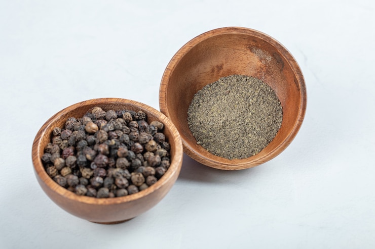 Photo gratuit bols de poivrons en grains et de poivre moulu sur une surface blanche.