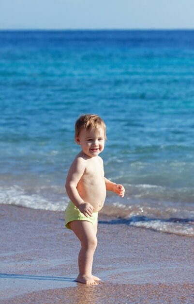Bon enfant en bas âge sur la plage de sable