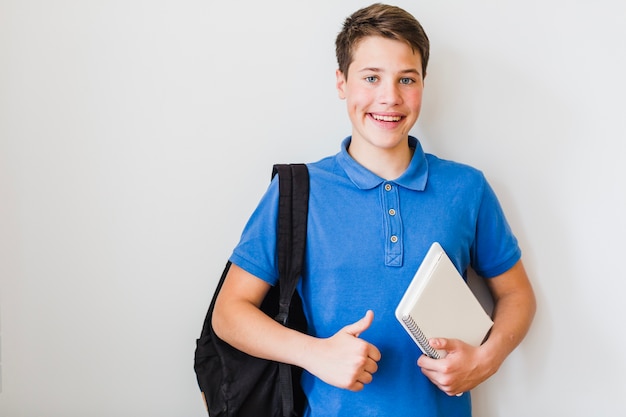 Bon étudiant posant avec un cahier et un sac à dos