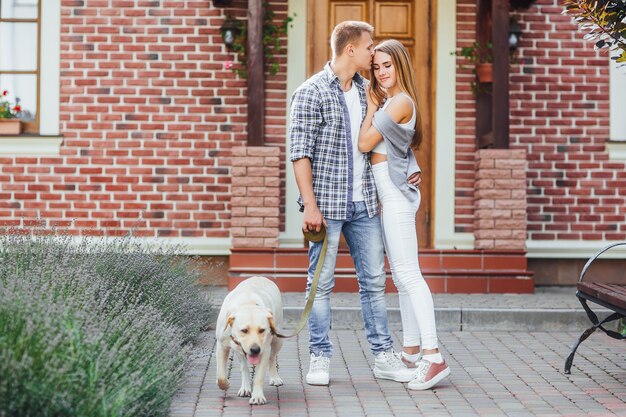 Bon moment! Jeune couple devant la grande maison avec beau labrador