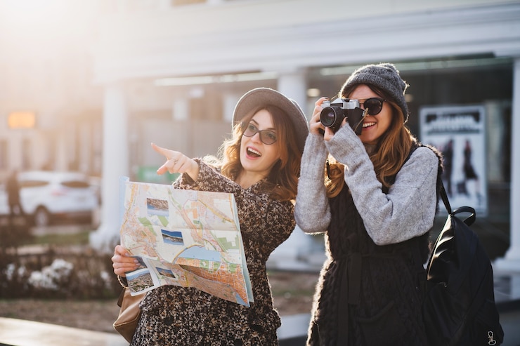 Photo gratuit bon voyage ensemble de deux femmes à la mode dans le centre-ville ensoleillé. jeunes femmes joyeuses exprimant la positivité, utilisant la carte, vacances avec des sacs, appareil photo, prise de photo, émotions joyeuses, bonne humeur.