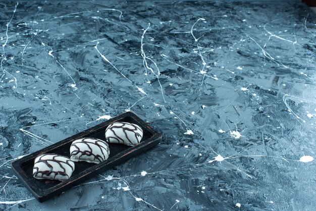 Bonbons sur une assiette en bois, sur la table bleue.
