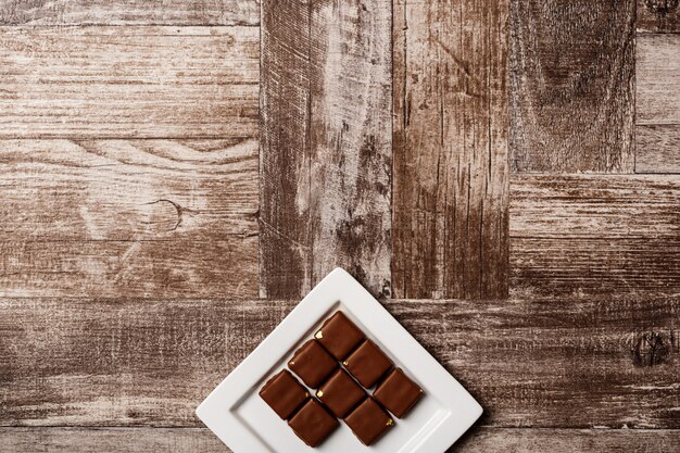 Bonbons au chocolat sur une plaque blanche sur bois