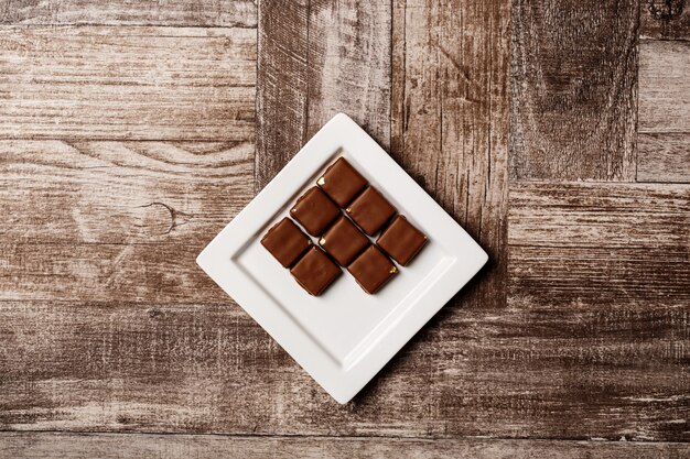 Bonbons au chocolat sur une plaque blanche sur bois