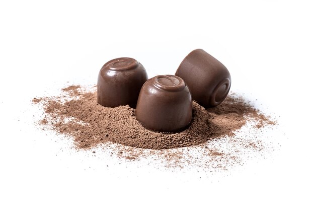 Bonbons au chocolat et poudre de cacao isolés sur fond blanc