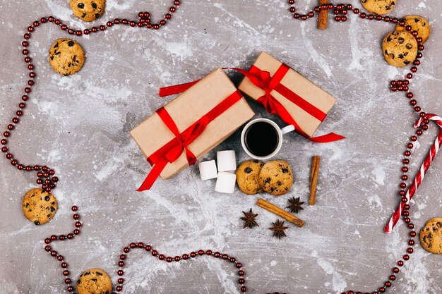 Bonbons blancs rouges, biscuits, guimauve, tasse de café et présent boîte se trouvent sur le sol gris