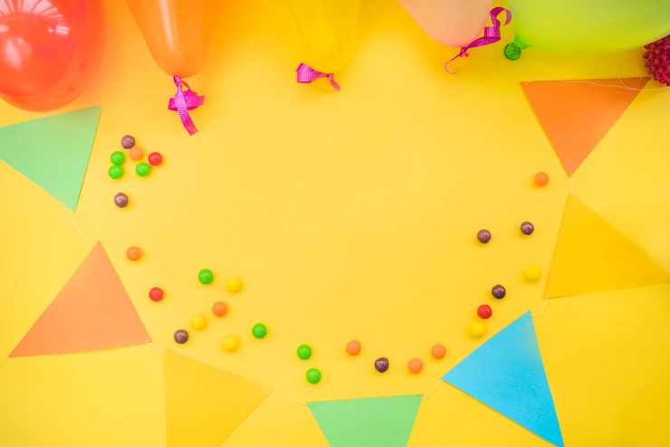 Photo gratuit bonbons colorés avec des banderoles et des ballons sur fond jaune