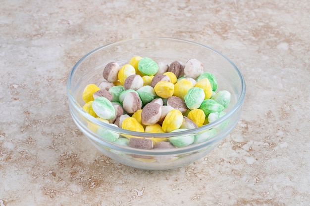 Bonbons colorés dans un bol, sur la table en marbre.