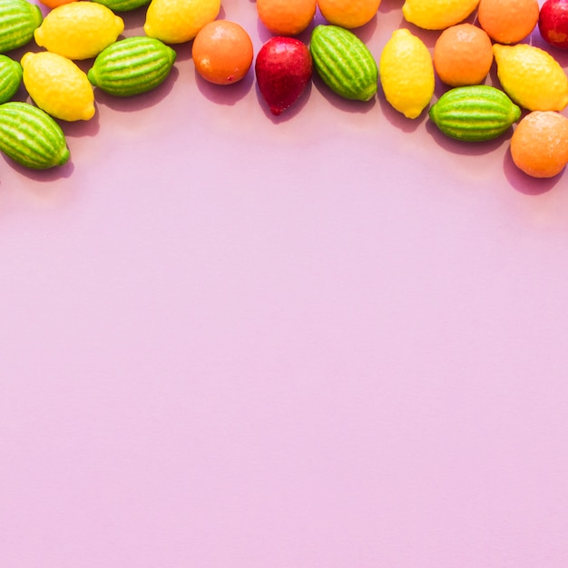 Photo gratuite bonbons colorés de forme de fruit formant le fond supérieur au-dessus de la toile de fond rose