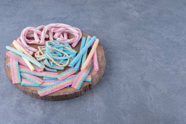 Bonbons colorés sous la forme d'une corde torsadée sur une planche sur une table en marbre.