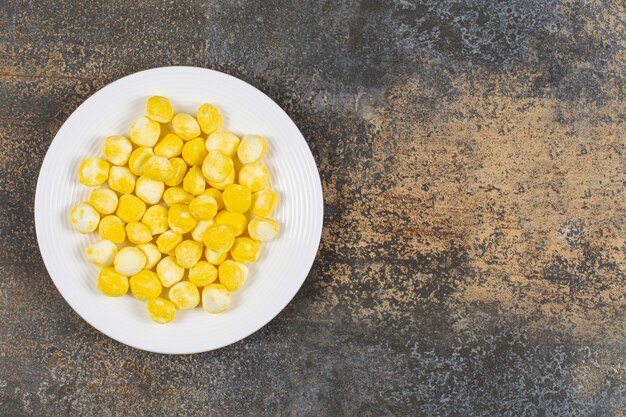 Bonbons durs jaunes sur plaque blanche.