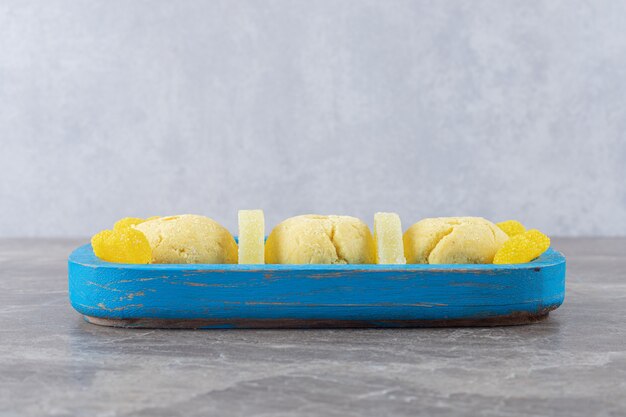 Bonbons à la gelée jaune et biscuits sur un petit plateau sur une surface en marbre