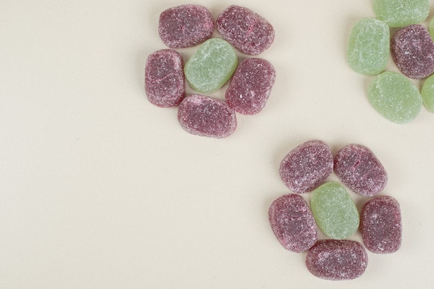 Bonbons à la gelée vert et violet sur une surface beige