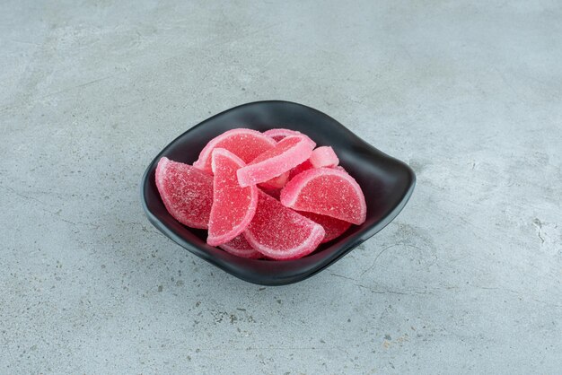 Bonbons à la marmelade rouge dans un bol noir. Photo de haute qualité