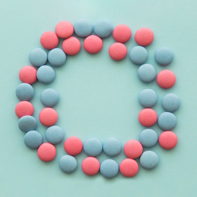 Photo gratuite bonbons roses et bleus disposés en forme circulaire sur le fond coloré