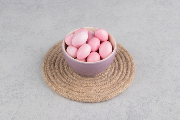 Bonbons roses dans la tasse sur le dessous de plat sur la surface en marbre