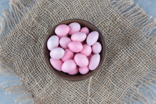 Bonbons roses dans la tasse sur le dessous de plat, sur la table en marbre.