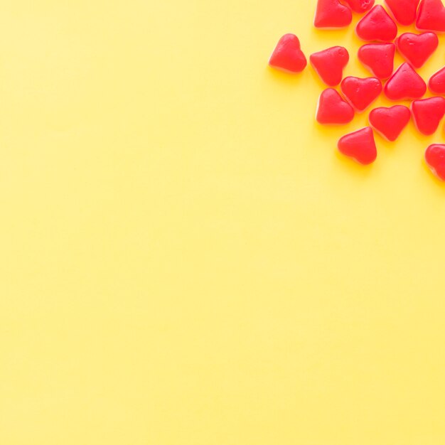 Bonbons rouges de forme de coeur sur le coin de la toile de fond jaune