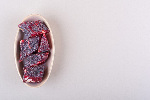 Bonbons rouges sucrés aux noix dans un bol beige sur fond blanc. photo de haute qualité