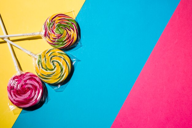 Bonbons sucettes colorées sur fond coloré rayé