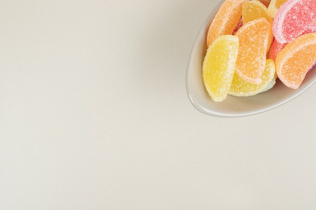 Bonbons sucrés à la gelée colorée dans un bol sur une surface beige