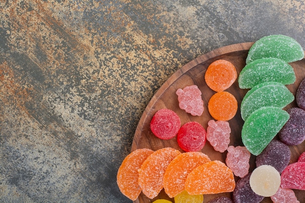 Photo gratuite bonbons sucrés à la gelée colorée sur plaque en bois. photo de haute qualité