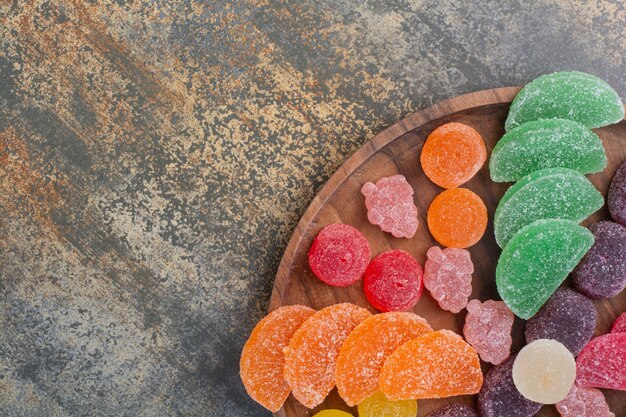 Bonbons sucrés à la gelée colorée sur plaque en bois. Photo de haute qualité