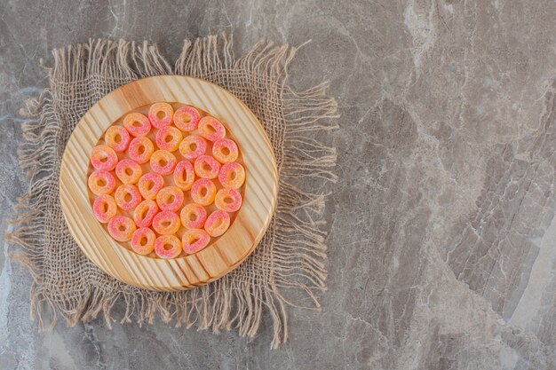 Bonbons sucrés à l'orange en forme d'anneau sur une plaque en bois sur un sac.