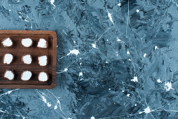 Bonbons tranchés sur une planche, sur la table bleue.