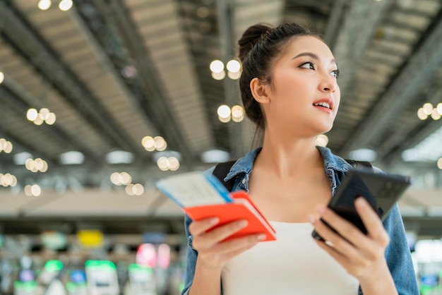 Bonheur souriant femme adulte asiatique porter un geste de la main en tissu décontracté montrant un passeport et un smartphone à écran vierge au terminal aitportfemme asiatique prête à voyager après la fin du verrouillage à l'aéroport