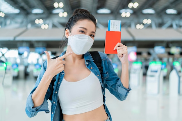 Bonheur souriant femme adulte asiatique porter un masque facial geste de la main montrant un passeport et un smartphone à écran vierge au terminal aitportfemme asiatique prête à voyager après le verrouillage ia plus à l'aéroport